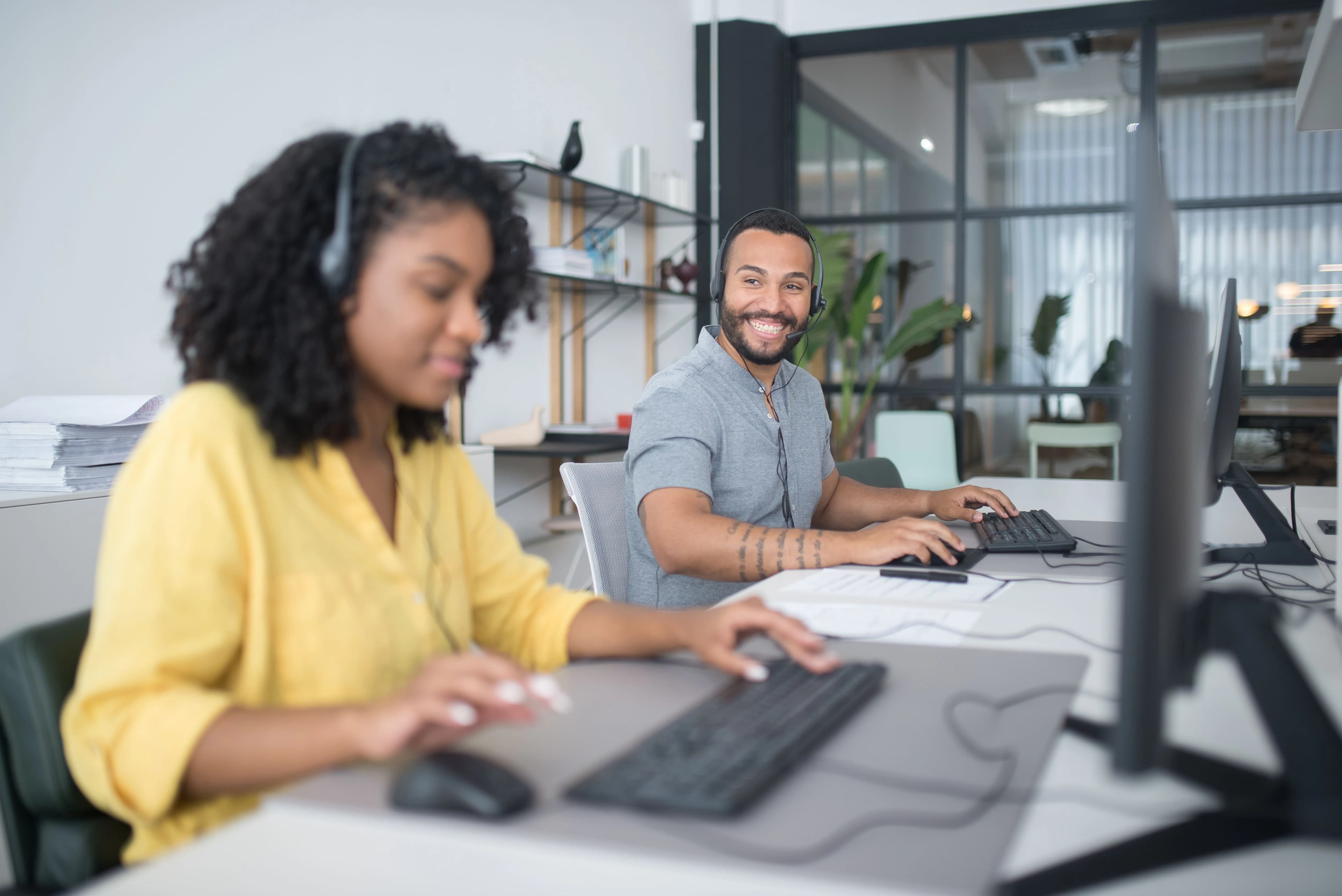 Two customer service team members answering calls on headsets